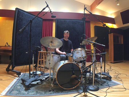 A man behind a drumkit in a studio